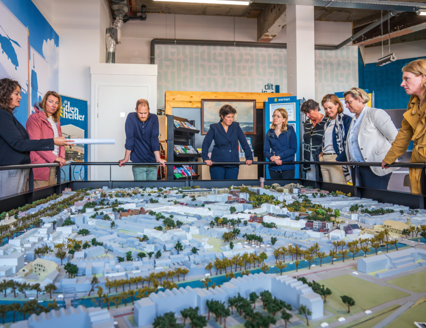 Deelnemers werkbezoek buigen zich over een maquette in Den Helder